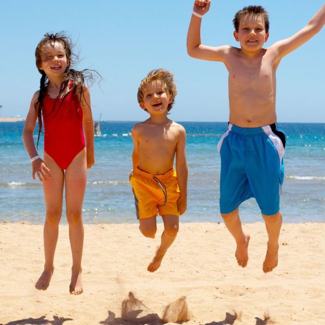 tres niños saltando en la playa